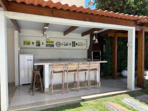 an outdoor kitchen with a bar with stools at Casa da Jana com piscina in Porto Seguro