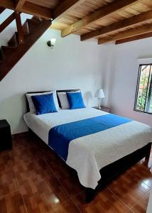 een slaapkamer met een groot bed met blauwe kussens bij SA Cabaña cómoda y acogedora in San Agustín