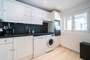 a kitchen with white cabinets and a washer and dryer at Brand new 2 bedroom in the heart of Cannes in Cannes