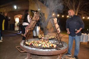 Ein Mann steht vor einem Grill mit Essen in der Unterkunft Catar Sensaciones in Chacras de Coria