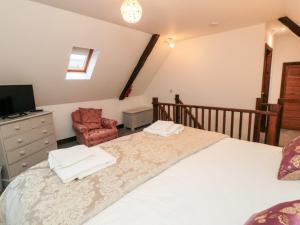 - une chambre avec un grand lit et une chaise dans l'établissement Mill Cottage, à Whitby