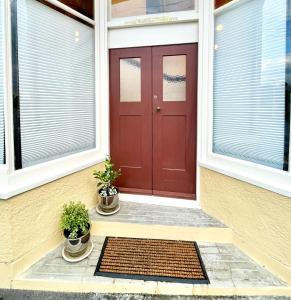 a red door on a house with two potted plants at Opoho Heritage Guest Suite in Dunedin