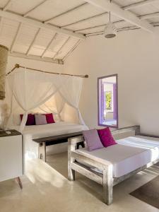 a bedroom with two beds and a couch and a mirror at Pousada Lagoa in Caraíva