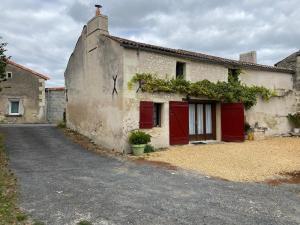 un antiguo edificio con puertas rojas y vides. en Gîte Vaudelnay, 2 pièces, 2 personnes - FR-1-622-64, en Vaudelnay