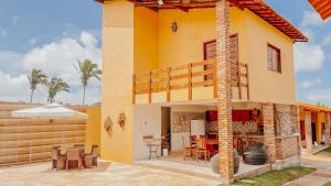 a yellow house with a patio and dining area at Pousada Sítio Machado in Viçosa do Ceará