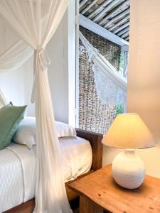 a bedroom with a bed and a table with a lamp at Pousada Lagoa in Caraíva