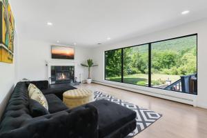 a living room with a black couch and a large window at Malkita’s Mountain View Villa in Woodbury