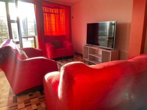 Il comprend un salon doté d'un mobilier rouge et d'une télévision à écran plat. dans l'établissement CASA HOSPEDAJE LAS MONTAÑAS, à Huancayo