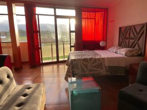 1 dormitorio con cortinas rojas, 1 cama y 1 sofá en CASA HOSPEDAJE LAS MONTAÑAS, en Huancayo