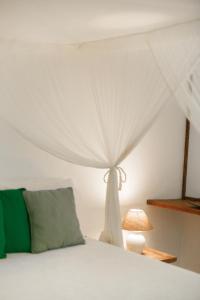 1 dormitorio con 1 cama con dosel blanco en Pousada Lagoa, en Caraíva
