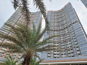 a palm tree in front of two tall buildings at Luxurious Flat 2BR in Gold Coast PIK Penjaringan in Jakarta