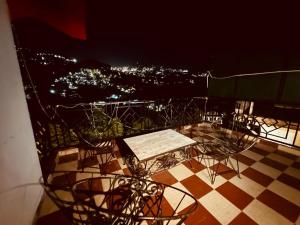 una mesa y sillas en un balcón por la noche en The Aston Hills - A Luxury Stay , Shimla en Shimla
