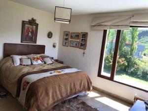 1 dormitorio con cama y ventana grande en La Escondida Tafi del Valle en Tafí del Valle