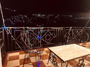 uma mesa e cadeiras numa varanda à noite em The Aston Hills - A Luxury Stay , Shimla em Shimla