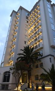 a large building with a palm tree in front of it at Monoambiente de Lujo Cores in Cochabamba