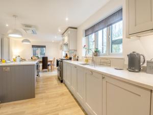 a kitchen with white cabinets and a large window at Walcot House Stables in Diss