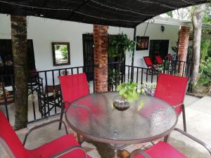 une table en verre et des chaises rouges sur la terrasse dans l'établissement RV Finca a 20 min de Neiva, à Neiva
