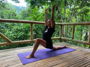 una mujer haciendo una pose de yoga en una esterilla de yoga en River Song's Hotel, en Mindo