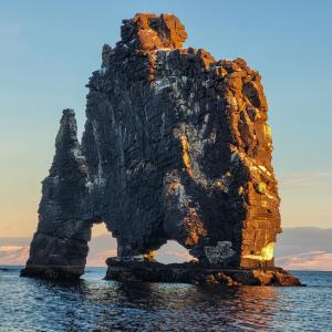 an island in the water with an arch in it at Hótel Hvítserkur in Hvammstangi