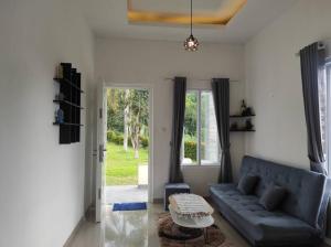 sala de estar con sofá azul y mesa en Villa BNA Curug Nangka Taman Sari Bogor, en Cibeunjing