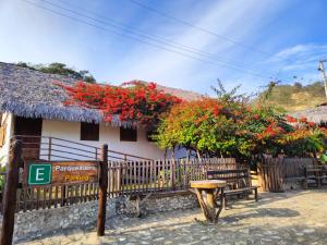 a building with benches and red flowers on it at Green Lodge - Ayampe in Ayampe