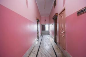 an empty hallway with pink walls and wooden floors at Hotel O Maa Laxmi Lodge in Bānkura
