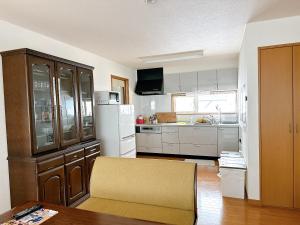 a kitchen with a wooden table and a kitchen with white appliances at 民宿にしかぐら in Higashikawa