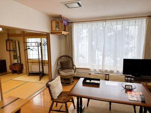 ein Wohnzimmer mit einem Tisch und einem großen Fenster in der Unterkunft 民宿にしかぐら in Higashikawa