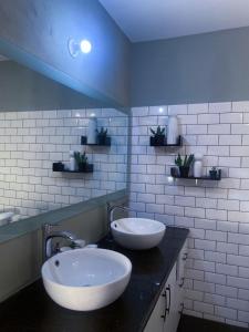 een badkamer met 2 witte wastafels en een zwart aanrecht bij House of Zen in Santa Cruz