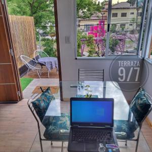 um computador portátil sentado numa mesa de vidro num quarto em Loft Terraza 9I7 Cochera en Excelente Ubicación em Villa Mercedes