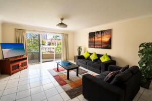 a living room with two couches and a flat screen tv at Key Largo Holiday Apartments in Gold Coast