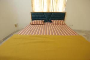 un letto giallo con due cuscini sopra in una stanza di ROHAN HOUSE a Nashik