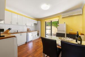 cocina con mesa y cocina con armarios blancos en Swan River Applecross Heathcote Park 1BR Villa, en Perth