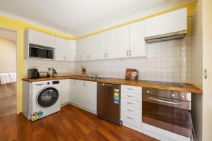 a kitchen with white cabinets and a washer and dryer at Swan River Applecross Heathcote Park 1BR Villa in Perth