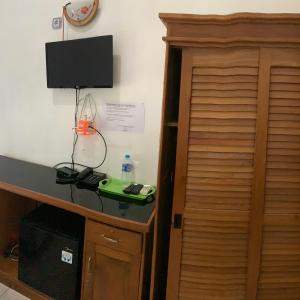 a room with a desk with a television and a cabinet at Hotel Nascar Famili in Palangkaraya