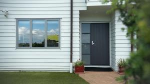 a house with a black door and a window at Te Rukutai in Auckland