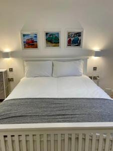 a bedroom with a white bed with three pictures on the wall at London Regent Studio Apartments in London