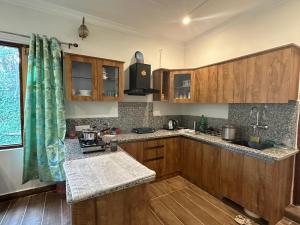 a kitchen with wooden cabinets and a sink at Kut House in Pālampur