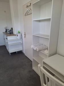 Habitación con estanterías blancas, lavabo y escritorio. en hoteliving Apartments Gießen-Süd, en Giessen