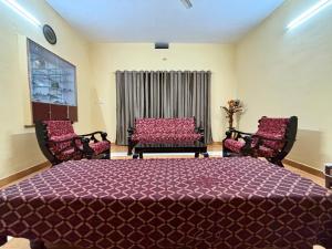 a bedroom with a large bed and two chairs at Kokaris Coorg Homestay in Kushālnagar