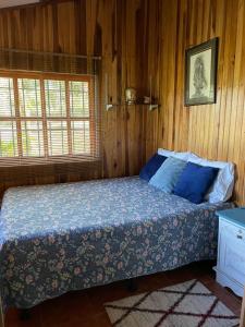 1 dormitorio con 1 cama en una pared de madera en Equipped cottage in Laguna Hule en Río Cuarto