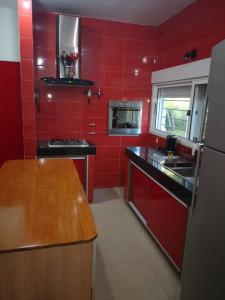 cocina roja con fregadero y fogones en Casa cero stress en Salto