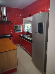 uma cozinha com paredes vermelhas e um frigorífico de aço inoxidável em Casa cero stress em Salto