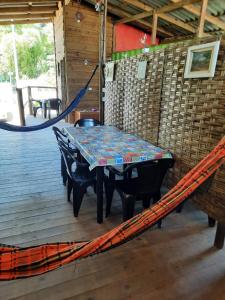 a table on a deck with a hammock at Recanto do Estaleiro in Ubatuba
