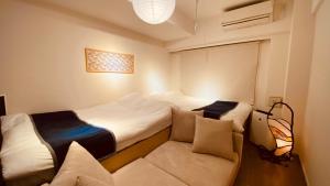 東京にあるSakura Retreat Ryokan- Haneda Gateway-澪のベッド2台とソファが備わる小さな客室です。