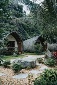 a small house with a thatched roof in a garden at Fairy Mountain Retreat in Ninh Binh