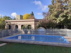 a swimming pool with a fence next to a building at Catar Sensaciones in Chacras de Coria
