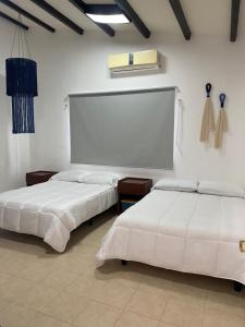 Dos camas en una habitación con paredes blancas. en Casa ALBU Telchac Puerto de Abrigo, en Telchac Puerto
