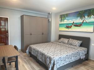 a bedroom with a bed and a painting on the wall at Patong Vacation Rentals - 28 SQM Studio Apartments - Located in the Heart of Patong with Kitchen, Private Bathroom, Seating Area, 65" Smart TV with Free WIFI in Patong Beach