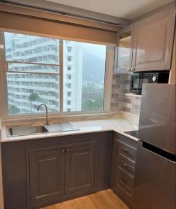 a kitchen with a sink and a large window at Patong Vacation Rentals - Studio Apartments - Located in the Heart of Patong with Kitchen, Private Bathroom, Seating Area, 65" Smart TV with Free WIFI in Patong Beach